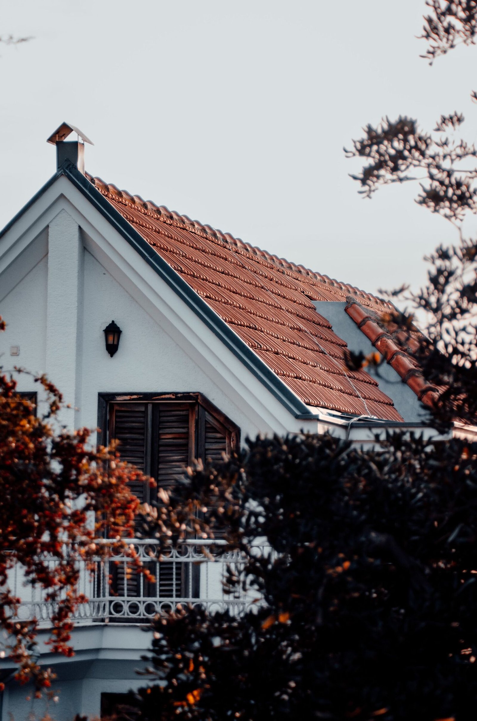 House with a red clay tile roof among trees